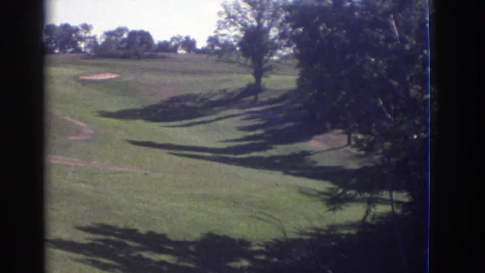 1972 Toronto home-movie view across a landscaped golf course with sand traps, trees, and strong afternoon-looking shadows.