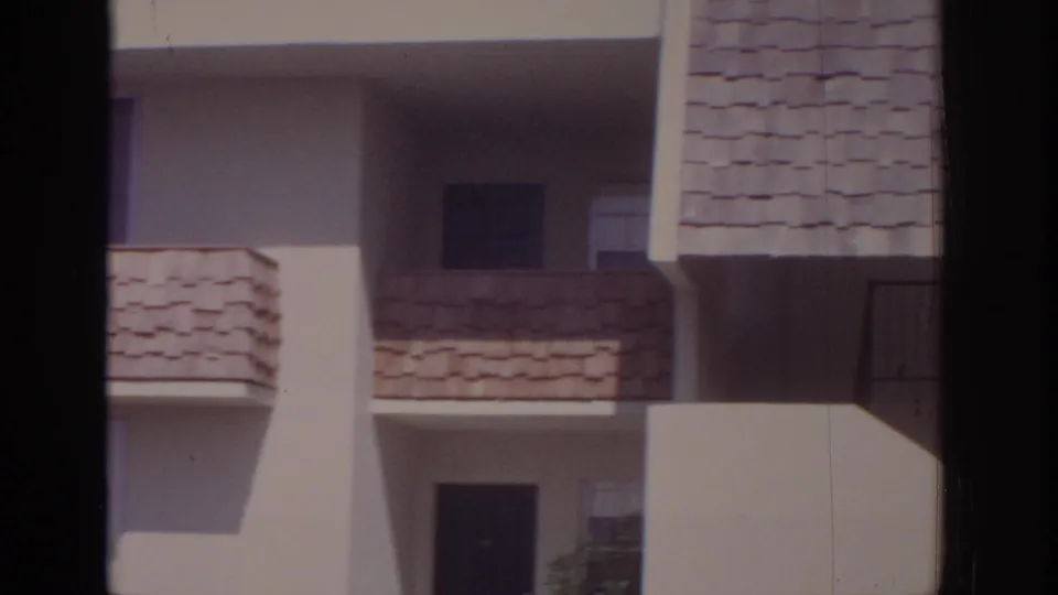 A 1973 Naples apartment exterior with stacked shingled balconies and recessed doors or windows, partly blocked by a dark vertical bar.