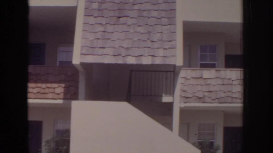 1973 Naples, Florida home-movie frame showing textured shingled balcony bands, dark doors, railings and cream stucco apartment walls.