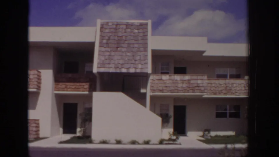 1973 Naples apartment exterior with flat roofline, textured balcony fronts, shaded entrances, and small landscaping beds.