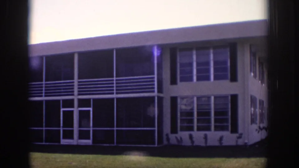 1973 Naples, Florida 8mm frame of a low-rise apartment facade with screened porch railings, window bays, and lawn foreground.