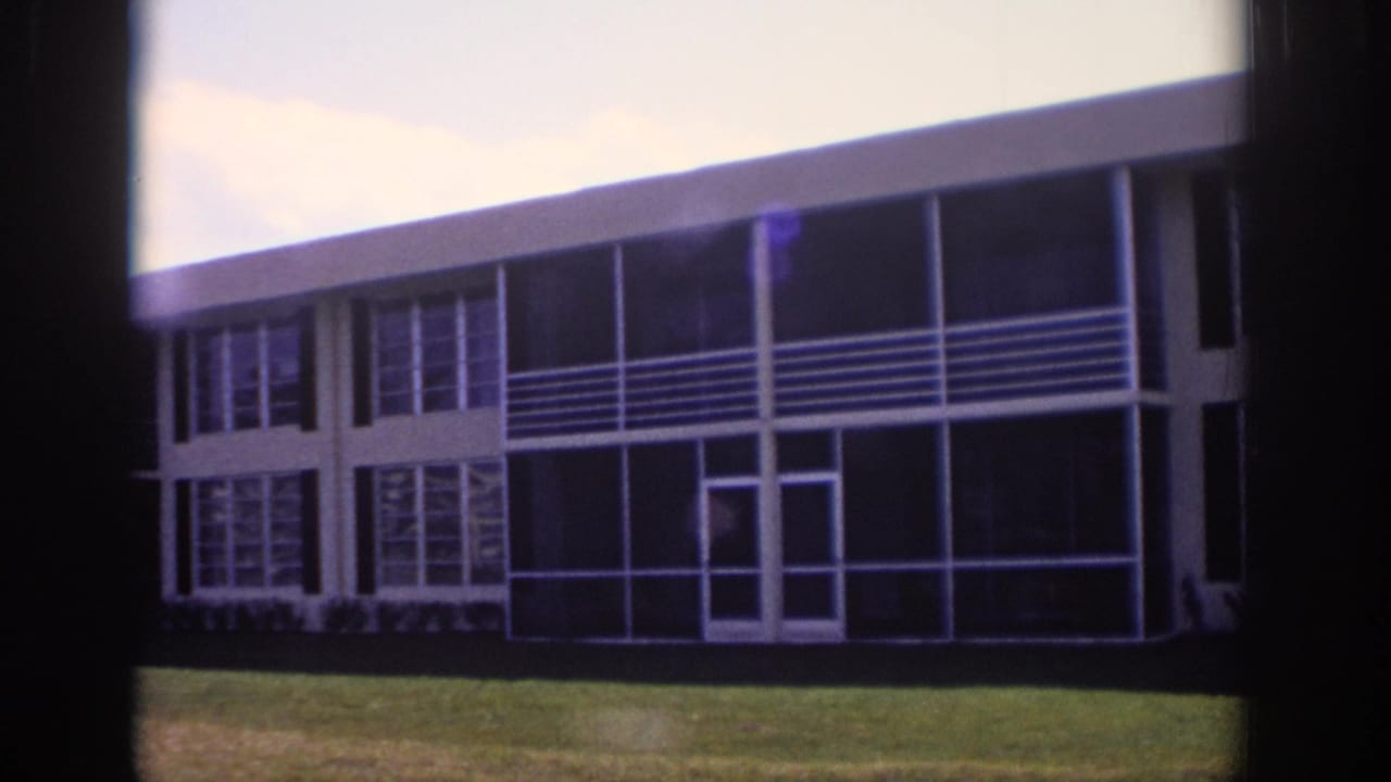 1973 Naples, Florida frame of the building facade with dark glass bays, white railings, and a flat roofline.