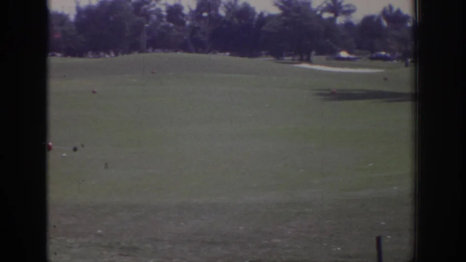 A wider 1973 Naples golf-course view shows clipped grass, small tee markers, trees, and a light path across the far side.