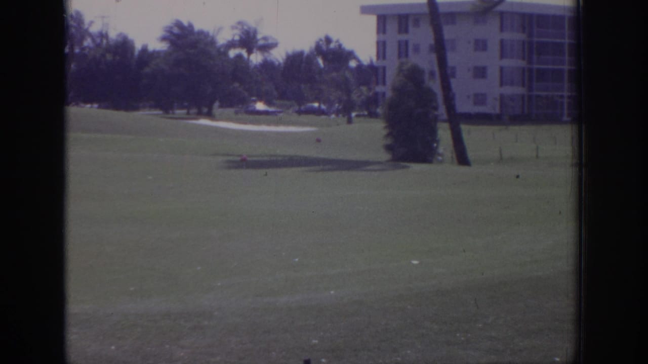 1973 Naples, Florida 8mm frame showing a golf course, bent palm trees, and resort buildings during strong wind.