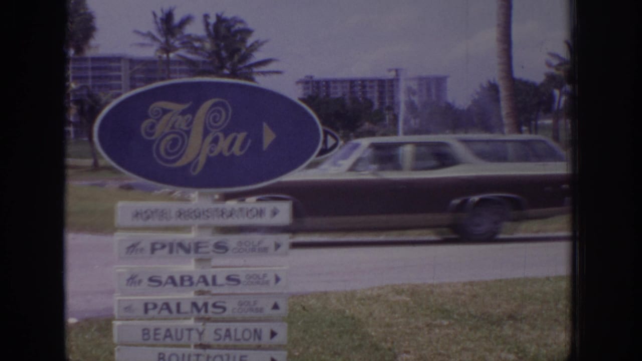 Station wagon passing behind The Spa sign and resort direction boards.