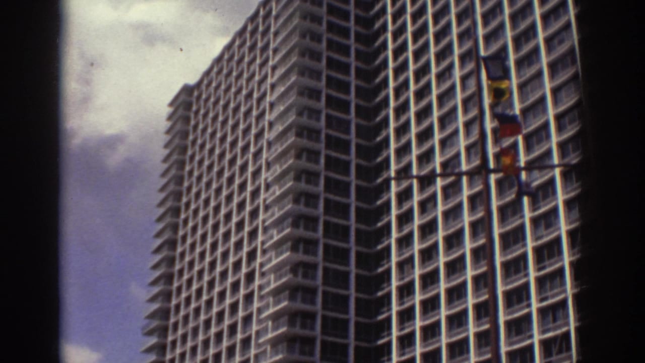 1974 Cleveland home-movie view of a large modern hotel tower, seen from below with flags in front and dark 8mm frame edges.