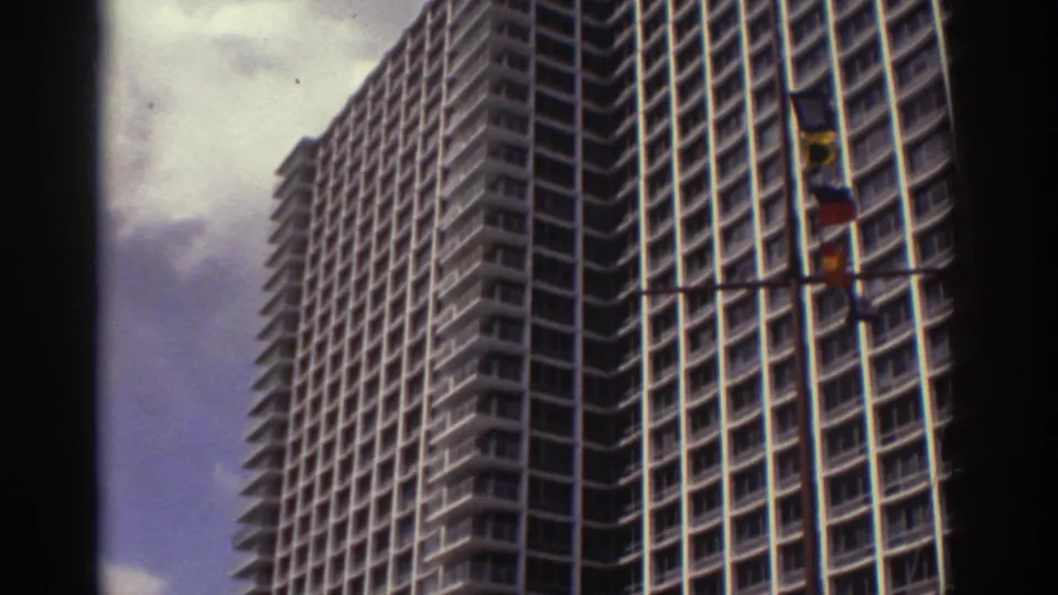 1974 Cleveland home-movie view of a large modern hotel tower, seen from below with flags in front and dark 8mm frame edges.