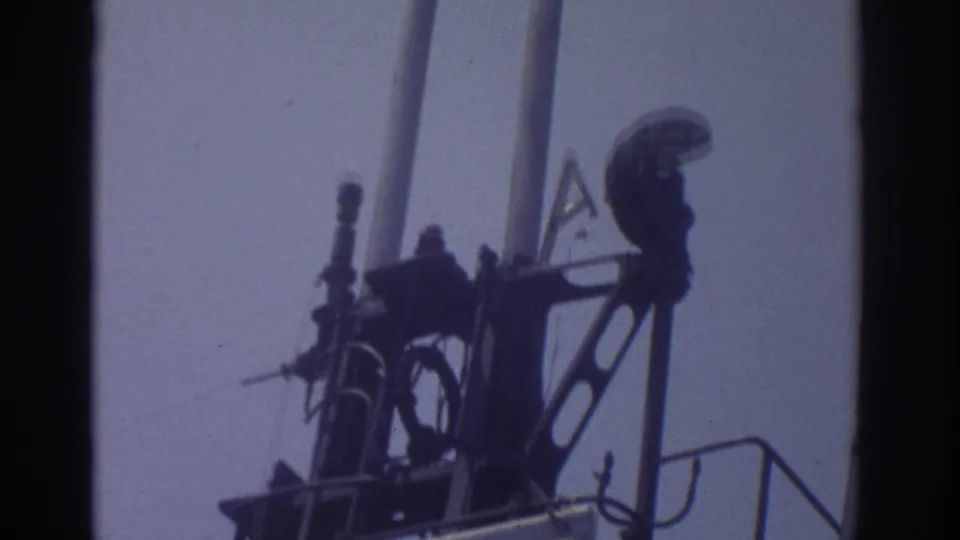 1974 Cleveland frame tilting upward past USS Cod tower equipment, railings, and mast forms against open sky.