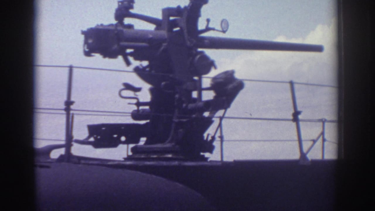 Deck-mounted naval cannon silhouetted against sky above a black submarine hull.