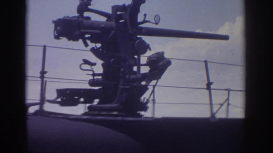 Close 8mm view of the submarine's mounted deck cannon at the Cleveland outdoor display, with railing and sky visible.