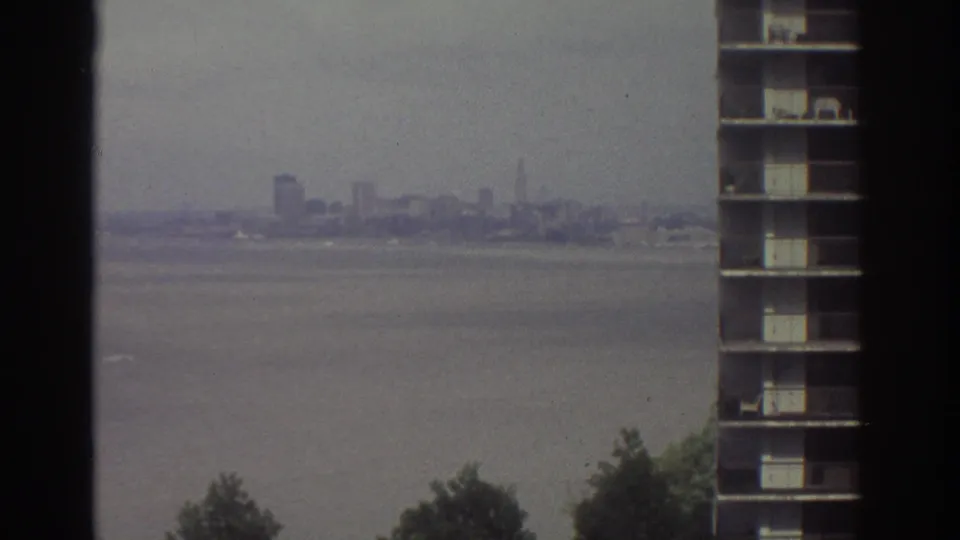 1974 Cleveland skyline viewed across water from a high position, with a tall building edge and dark film borders in frame.