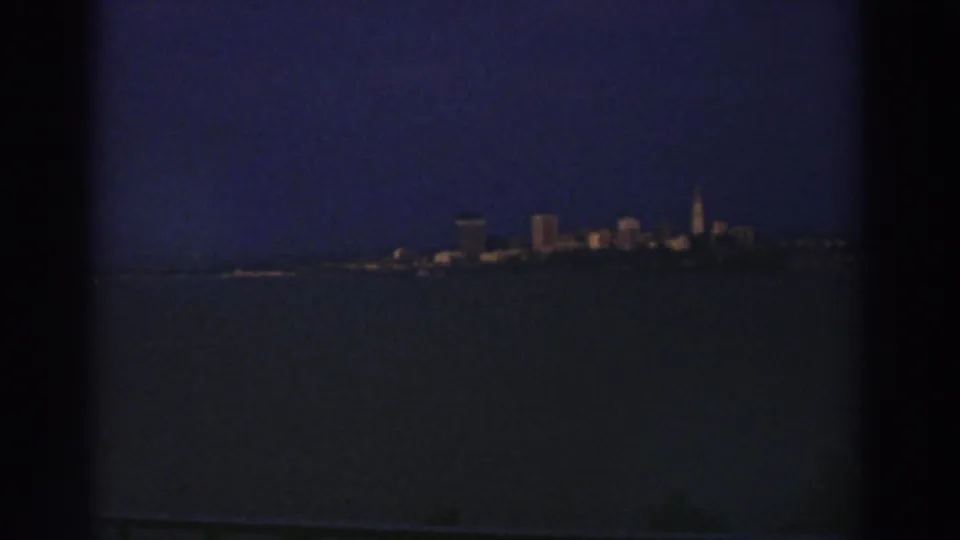Likely Cleveland, Ohio skyline viewed from across water in a grainy 1974 8mm nighttime frame.