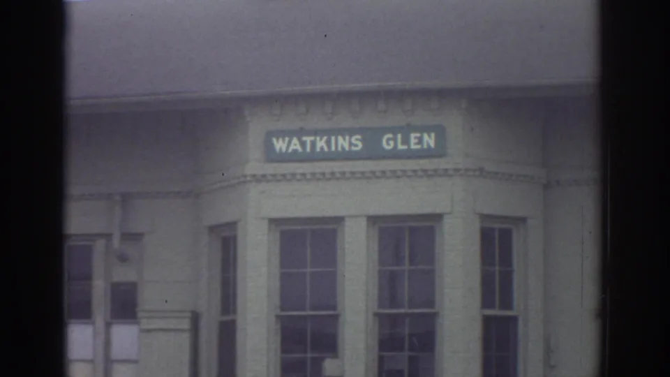 The final frame holds on the Watkins Glen sign over tall windows, with soft focus and faded 8mm color visible across the building front.