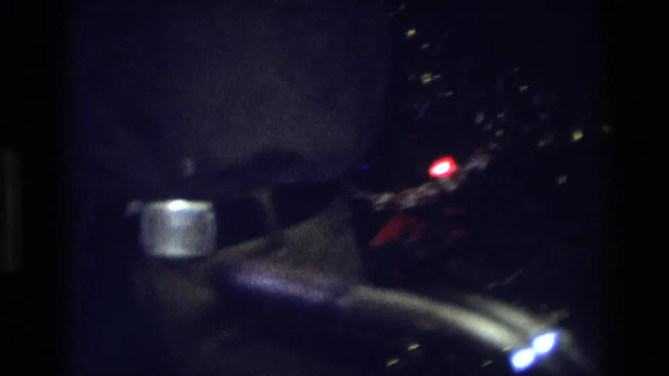 Dark 8mm frame from the 1975 Atlanta holiday interior, with tree lights and a partial figure visible in soft focus.
