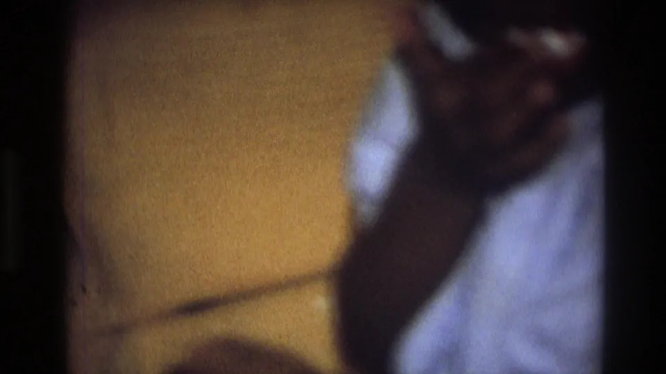 A soft, close 8mm frame shows part of the sofa and the child moving near a white object or clothing.