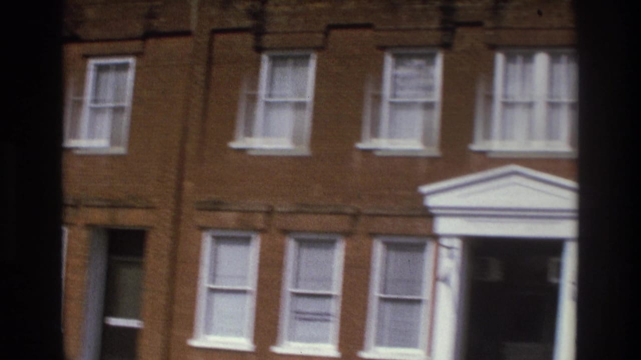 Brick building facade with white-trimmed windows and a columned entrance.