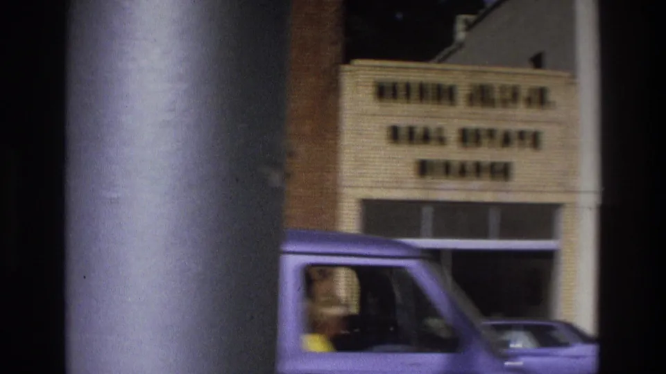 1975 Atlanta home-movie frame showing a storefront sign above a parked van, partly blocked by a dark foreground edge.