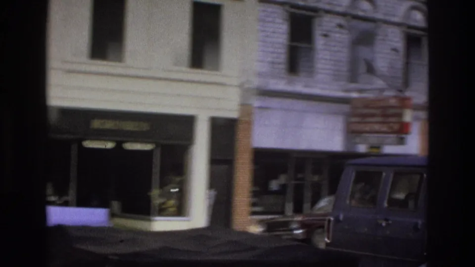 1975 Atlanta street scene with storefront windows, building signs, brick facades, and a dark van along the curb.