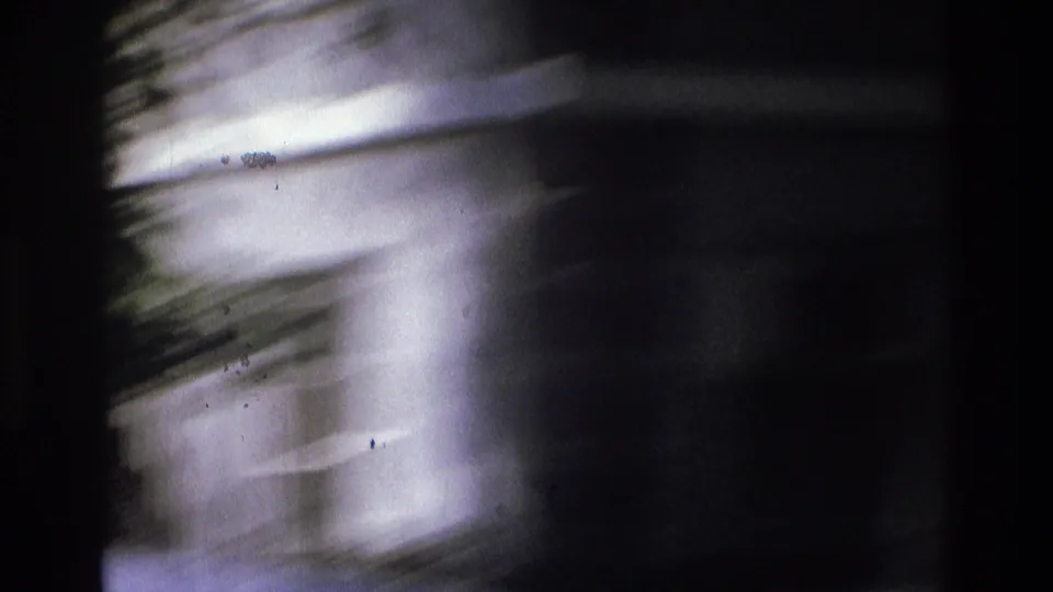 Soft, motion-blurred close view of white exterior columns, likely filmed as the camera turns from the street.