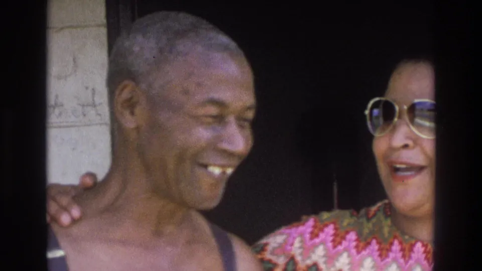 Close 1975 Atlanta home-movie view of a smiling older man in suspenders beside a woman in large glasses and a colorful top.