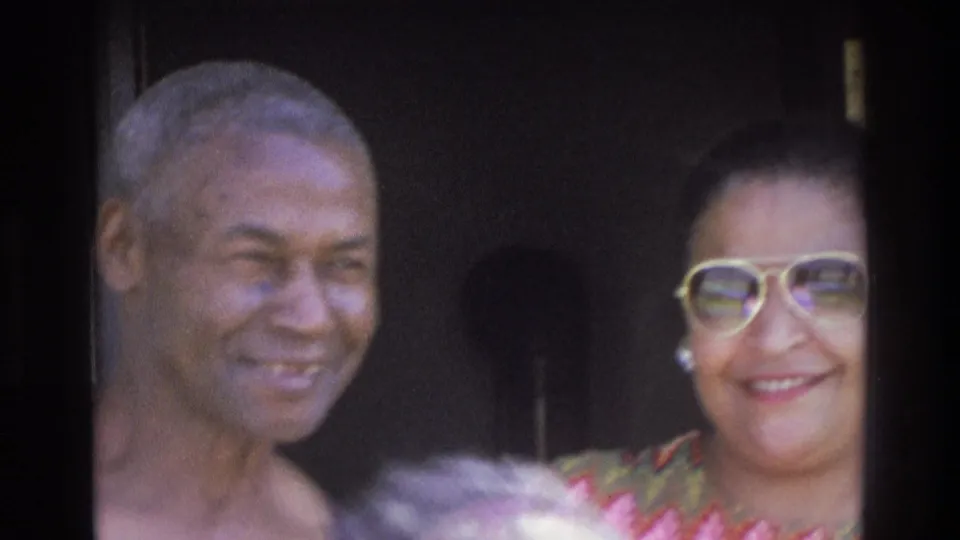 1975 Atlanta home-movie frame showing two adults smiling close together outside, partly framed by a dark doorway.