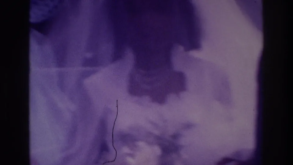 Atlanta 1975 home-movie frame showing blurred wedding figures, likely the bride and groom with guests, in a scratched purple 8mm image.