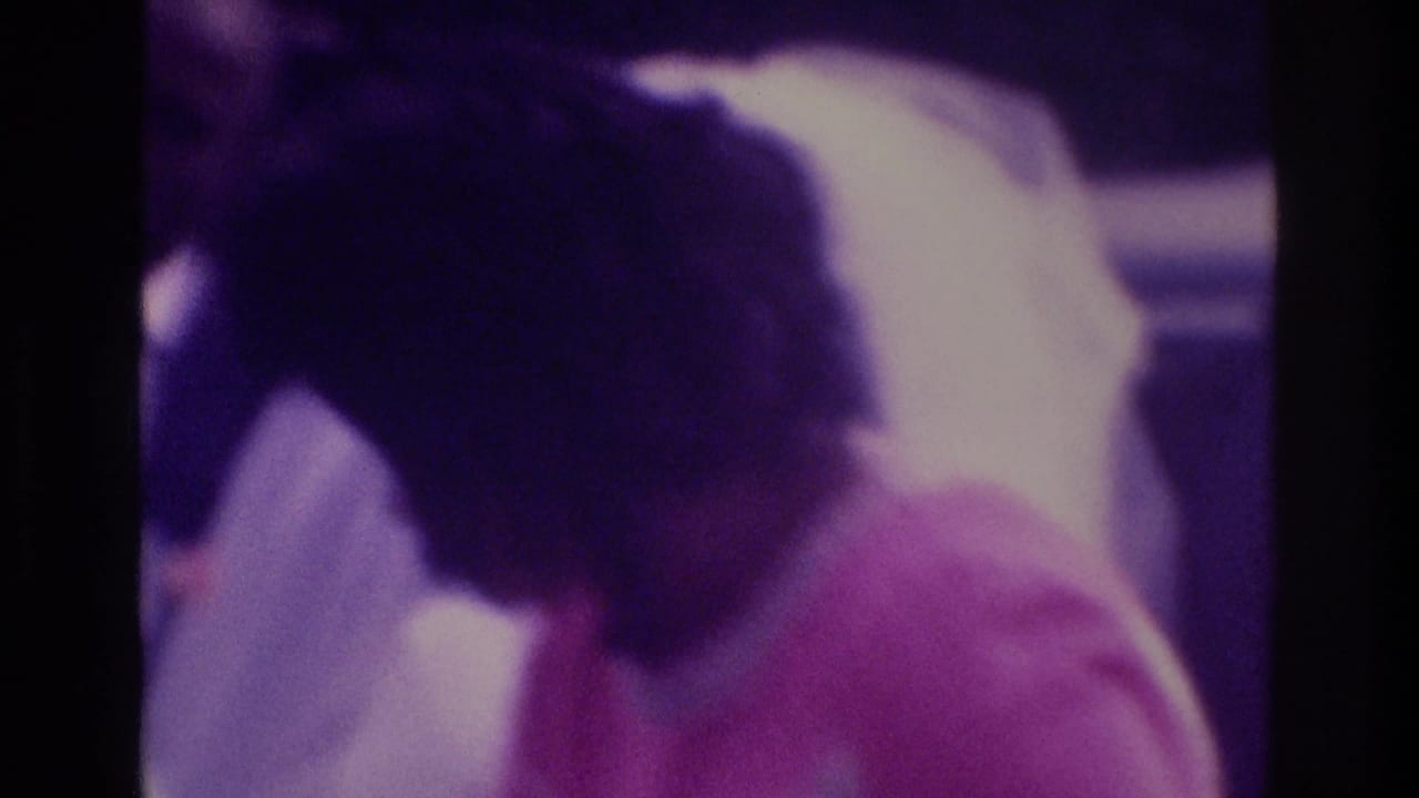 1975 Atlanta wedding home-movie frame with the bride leaning toward a small child in pink beside the groom.