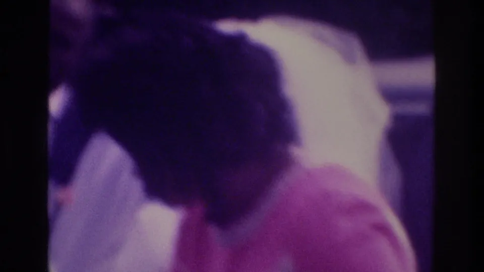 1975 Atlanta wedding home-movie frame with the bride leaning toward a small child in pink beside the groom.