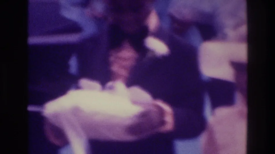 1975 Atlanta wedding home-movie frame with the groom holding white fabric while the bride stands close in her veil.
