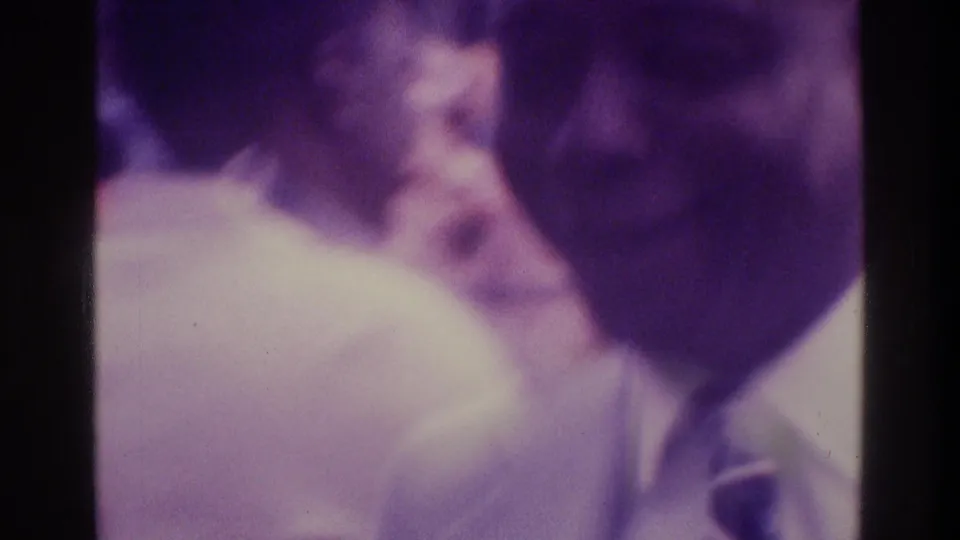 Purple-shifted 1975 Atlanta frame with a blurred crowd and a suited man partly visible at the right edge of the shot.