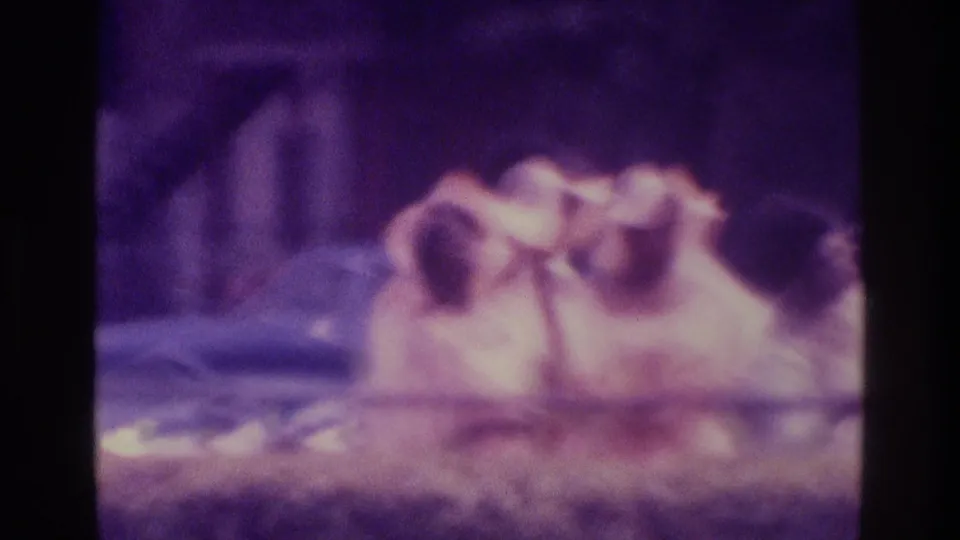 1975 Atlanta home-movie frame showing a man in sunglasses leaning back or reclining, rendered with soft focus and aged purple film color.