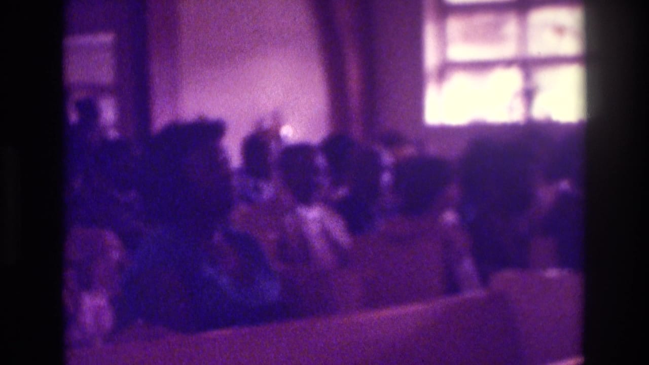 1975 Atlanta church-service frame with a seated congregation seen from the rear under strong purple color shift.