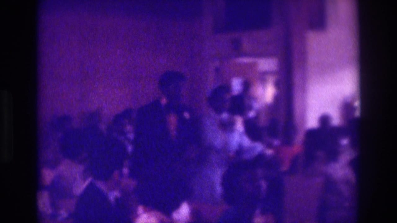 1975 Atlanta 8mm frame showing the couple walking through a crowded indoor wedding aisle.