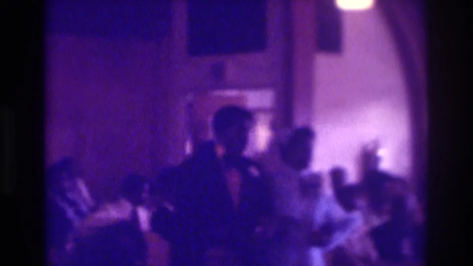 Soft 8mm home-movie view of the wedding couple among guests in an Atlanta indoor ceremony setting.