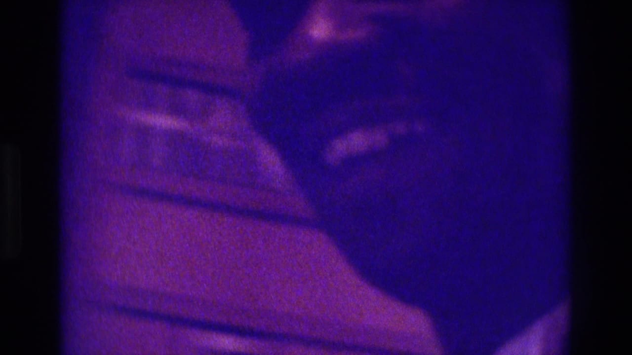 Close 1975 Atlanta home-movie frame showing a partial indoor figure and clothing detail in soft, purple-blue 8mm color.