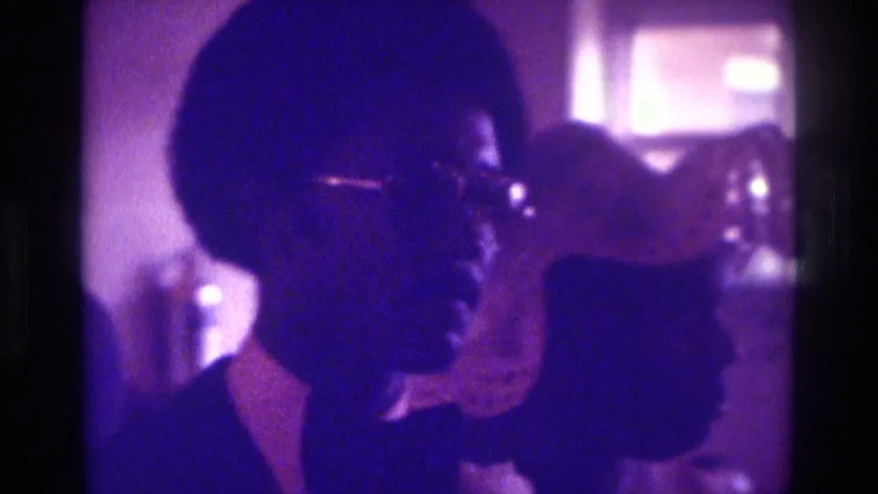 1975 Atlanta 8mm frame showing the groom-like figure in profile with a woman in white partially visible beside him.