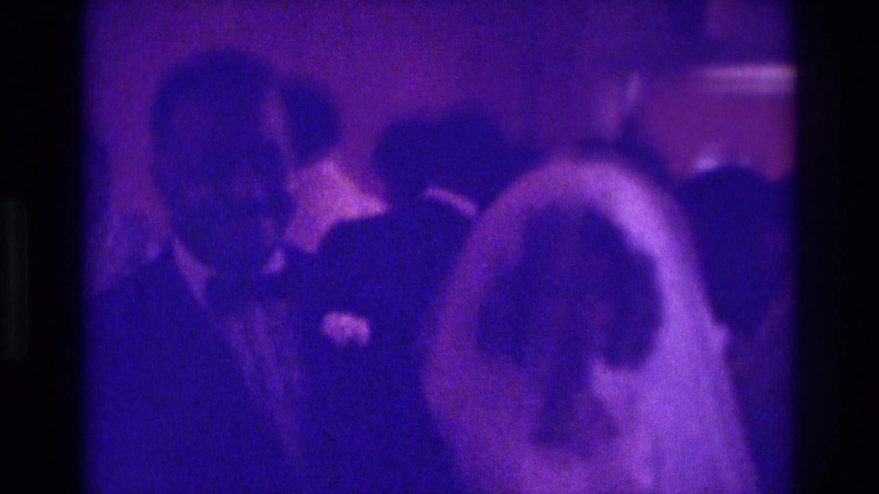 Bride and groom or male guest seen close together among reception guests.