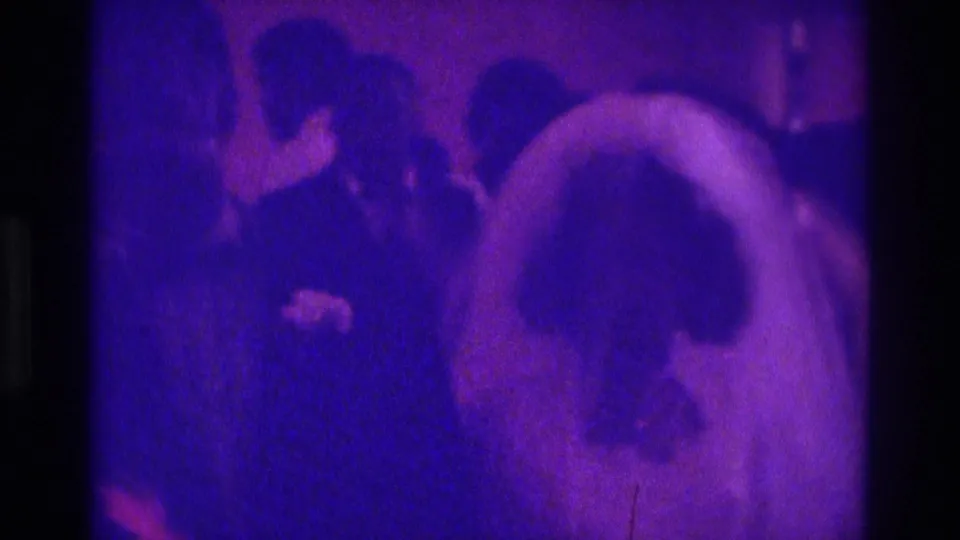 Purple-toned 1975 Atlanta wedding reception frame with the bride's veil in the foreground and guests behind her.