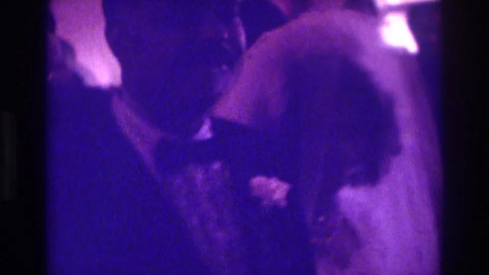 1975 home-movie frame showing the newlyweds dancing in profile in a dim Atlanta reception interior.