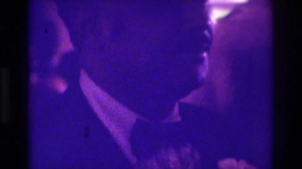 Soft, grainy 8mm frame of the groom and bride dancing closely at a 1975 Atlanta wedding reception.