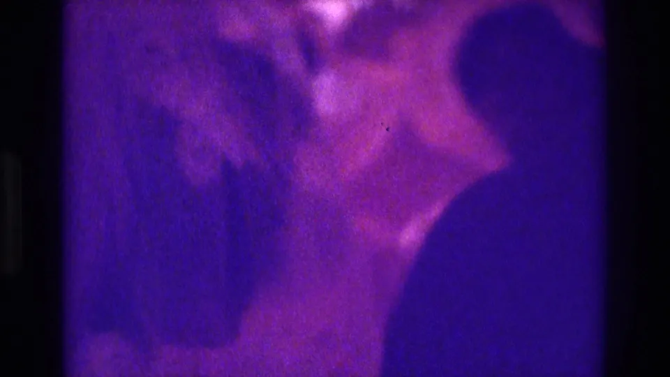 1975 Atlanta 8mm frame with the bride's veiled profile and escort close together under strong purple-blue lighting.