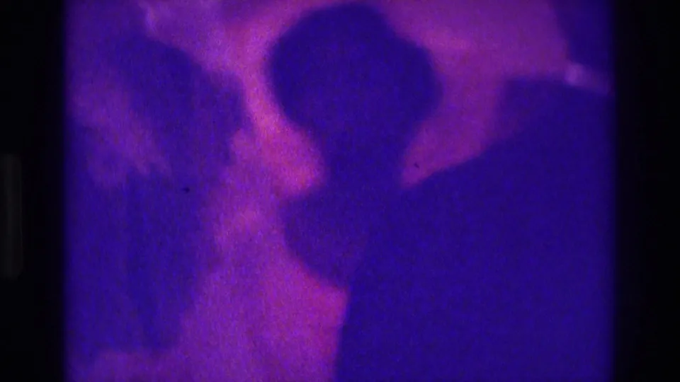 1975 Atlanta 8mm frame with purple-magenta cast showing silhouetted wedding guests or party members in formal attire indoors.
