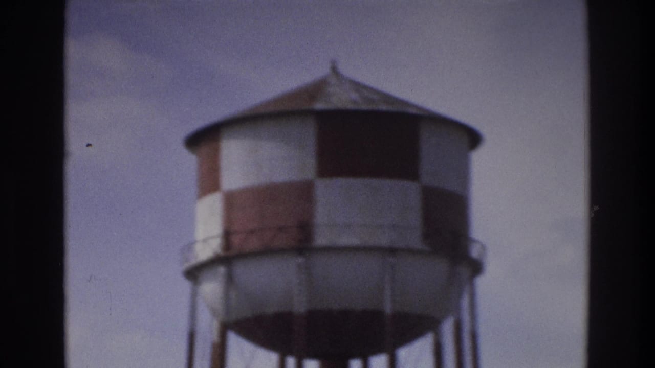 Red-and-white checkered water tower against a pale sky.