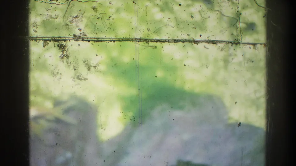 1975 Atlanta 8mm frame with a blurred person close to the camera, pale clothing, and soft green outdoor background.