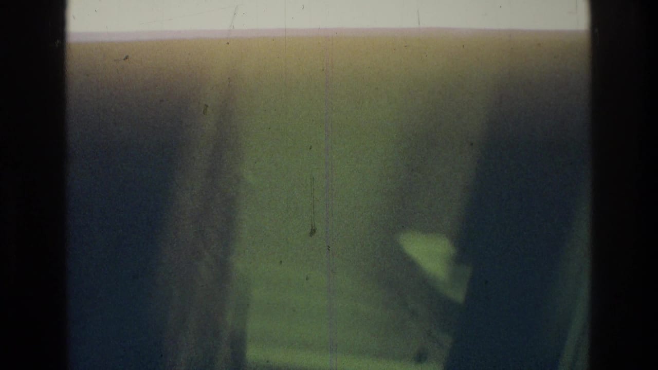 Two dark human figures appear close to the lens, with one light shape near the right side.