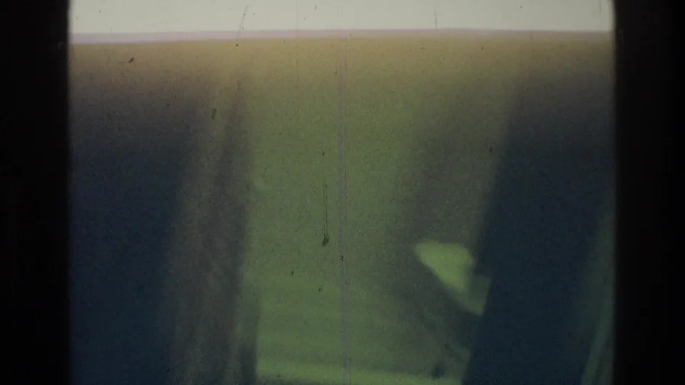 1975 Atlanta 8mm frame showing two indistinct people close to the camera in dark, soft-focused exposure.