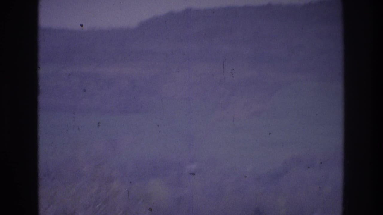 1975 Atlanta-area 8mm frame showing dense fog over distant low hills, with dark vertical film borders and soft grain.