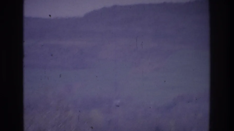1975 Atlanta-area 8mm frame showing dense fog over distant low hills, with dark vertical film borders and soft grain.