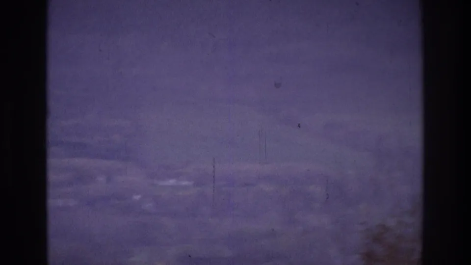 1975 Atlanta-area 8mm frame with hazy hills and faint vegetation seen through purple-blue fog and film wear.