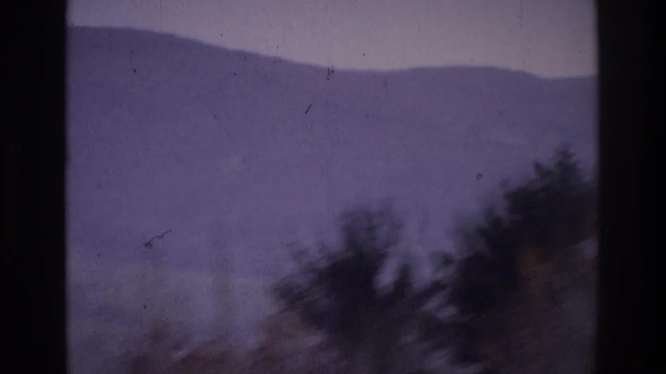 1975 Atlanta-area 8mm frame with a fog-softened hillside and dark tree silhouettes along the lower right edge.
